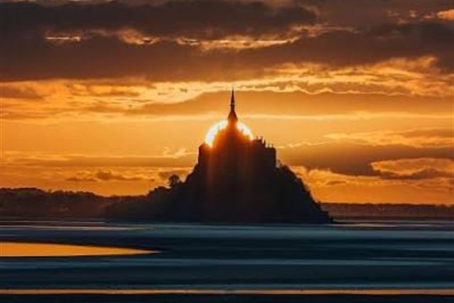 Le soleil derrière la flèche du Mont Saint-Michel